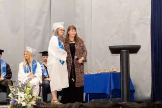 young woman in cap and gown accepting award