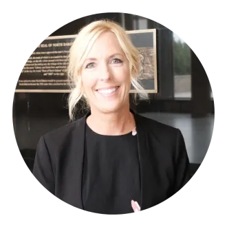 woman standing for a headshot wearing a black suit with her hair pulled back