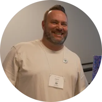 Man wearing white shirt and a name tag, smiling for photo.