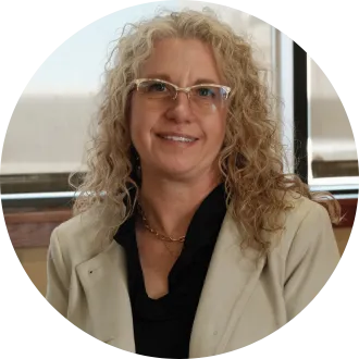 Portrait of Dawn Ressler, physical therapy assistant with Mandan Public Schools and North Dakota United's 2027 Education Support Professional of the Year. She smiles at the camera while wearing a light-colored blazer and glasses.