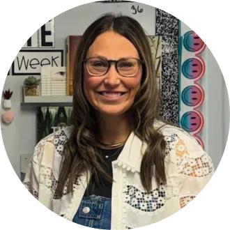 Portrait of Frannie Tunseth, North Dakota's 2026 Teacher of the Year and a reading and math teacher at May-Port CG Middle School. She smiles in her classroom while wearing glasses and a white lace cardigan over denim overalls.
