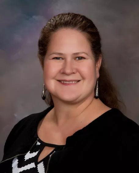 headshot of woman with black top and hair pulled back