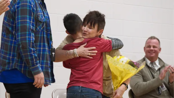 Woman hugging elementary school student holding flowers