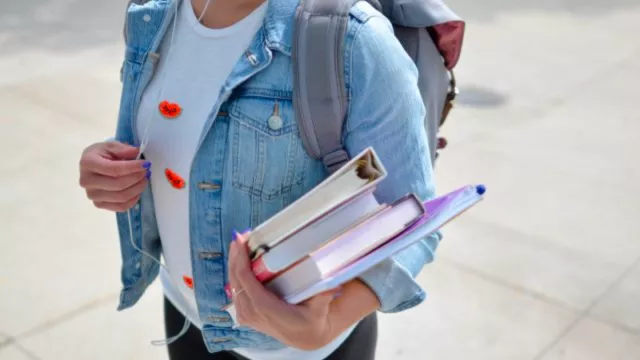 woman carrying binders walking to college
