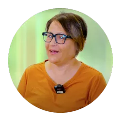 woman with short hair and glasses wearing an orange top