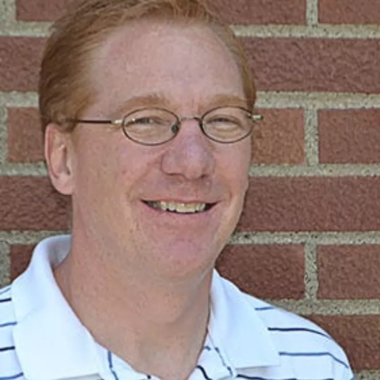 ND United VP of Public Employees smiles for a picture. A brick wall can be seen in the background.