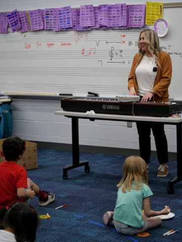 Risha Allen plays a portable piano in front of her class.