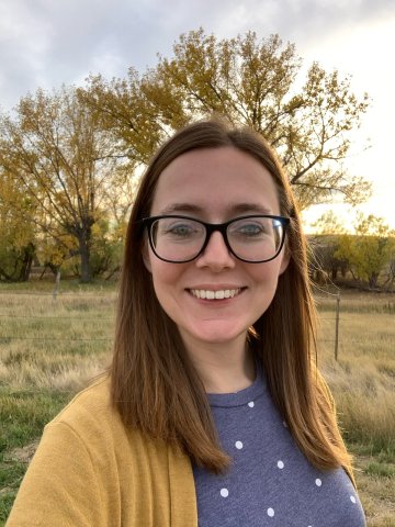 headshot of woman standing outside with trees behind her