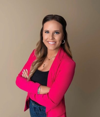 woman wearing blazer with her arms crossed smiling